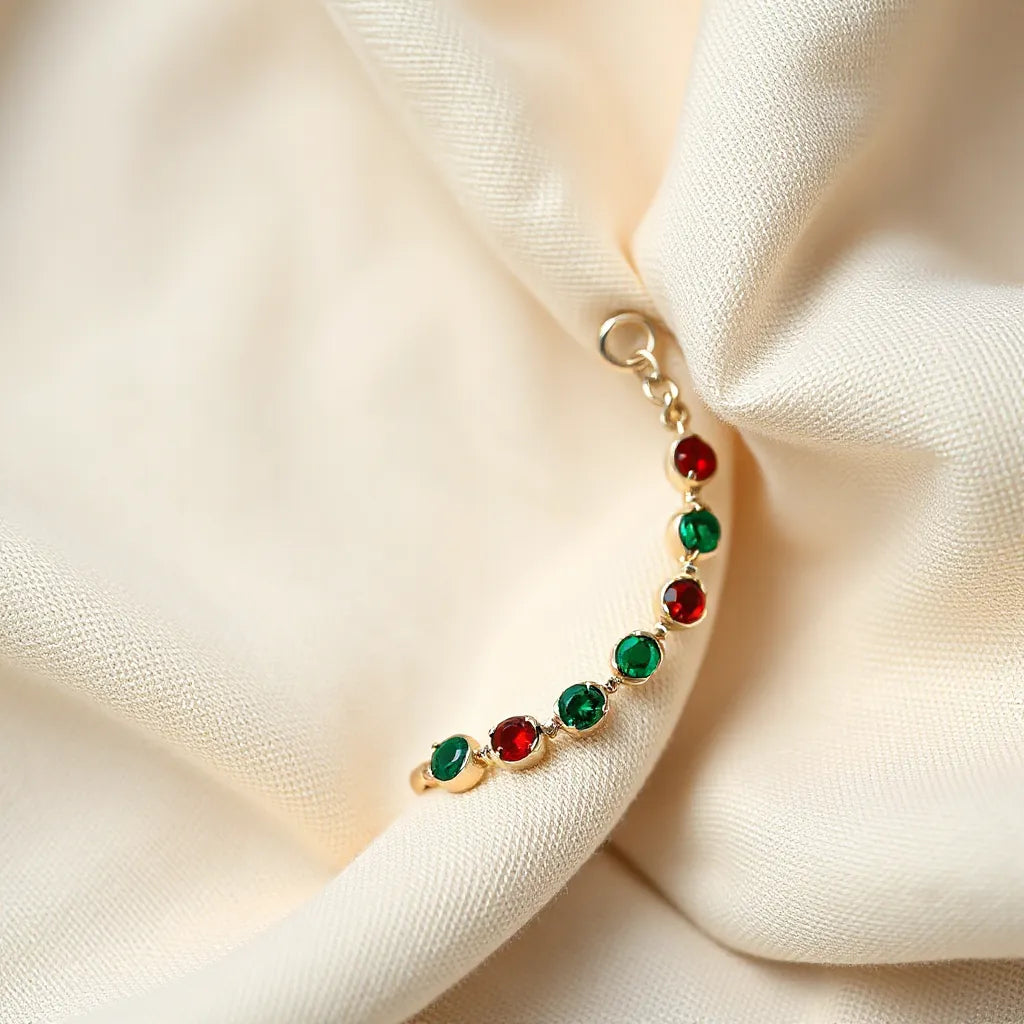 Red and green linked ring stone anklet with small gemstone-like accents on neutral fabric