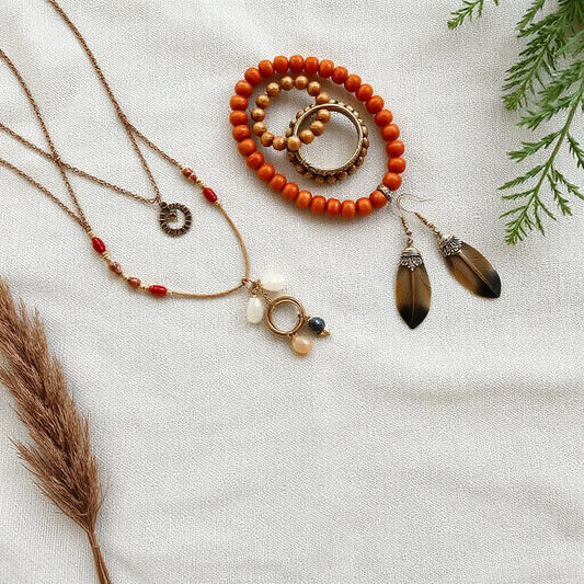 Layered bohemian-style necklaces, rings, and dangling earrings displayed on linen with warm natural light.